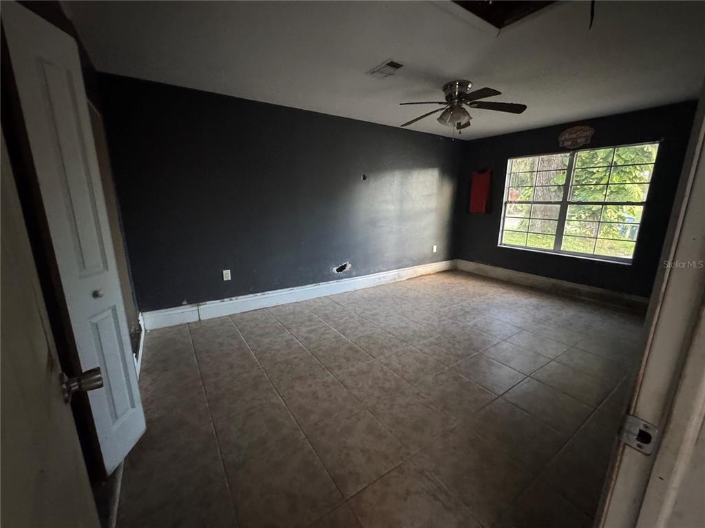 An empty bedroom features dark gray walls, tile flooring, a ceiling fan, and a window — 4005 CASCADE LANE, LABELLE, FL