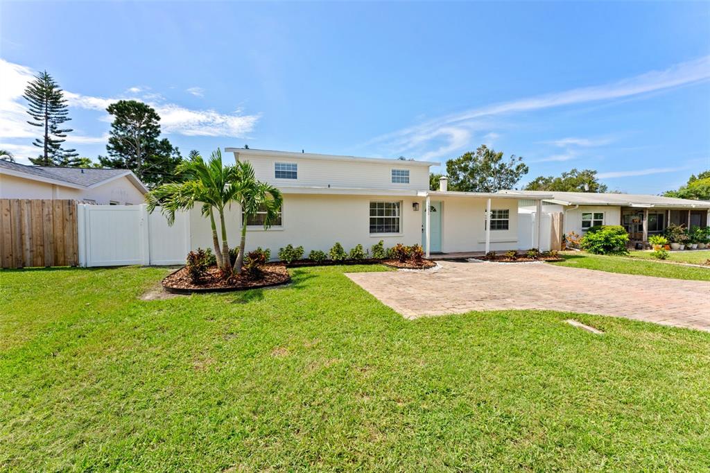 A single-story house with a light-colored exterior, a paved driveway, and a palm tree — 3298 21ST AVENUE SW, LARGO, FL