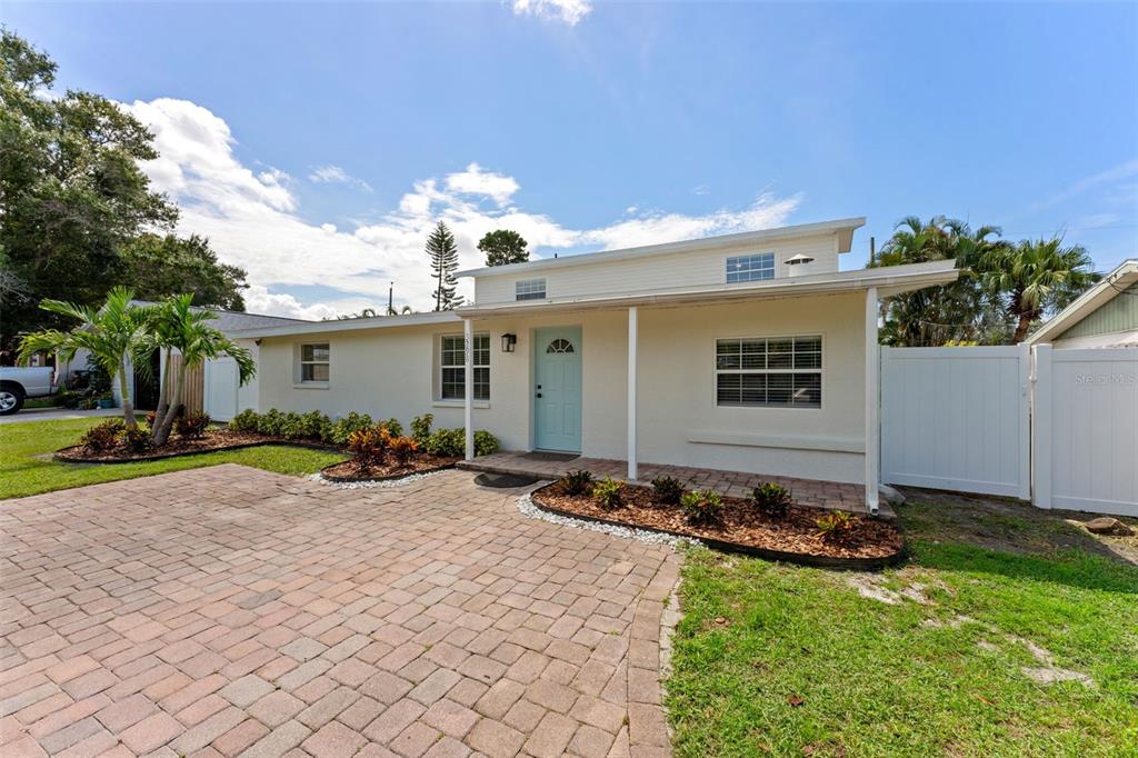 A single-story house with a light-colored exterior, a light blue front door, and a paver driveway — 3298 21ST AVENUE SW, LARGO, FL