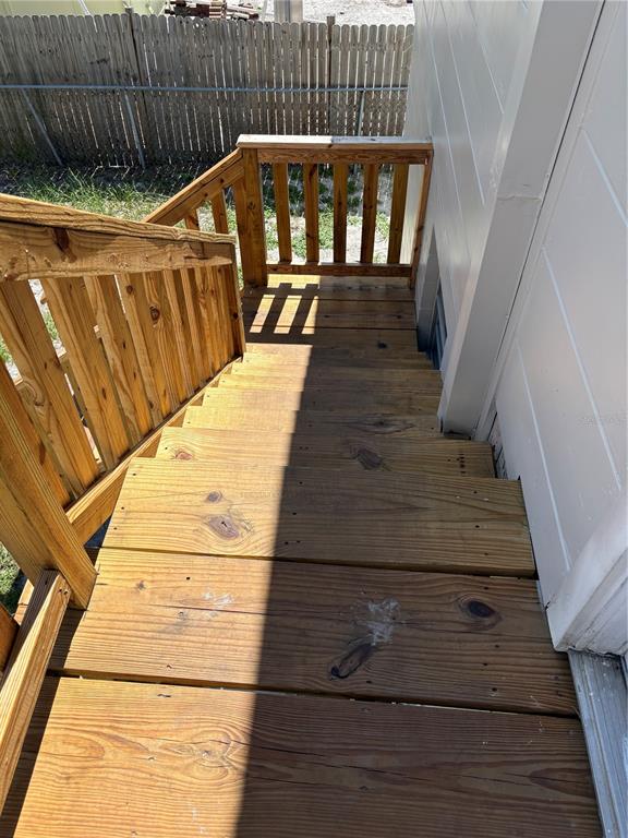 A wooden staircase with a railing leads down to a fenced outdoor area — 1100 JAMELA DRIVE UNIT B, OCOEE, FL