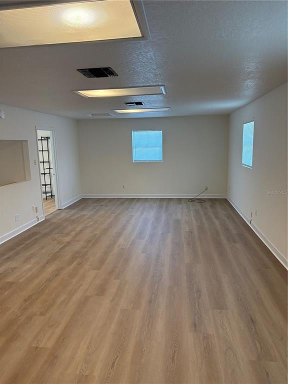 An empty room with light wood-look flooring, white walls, and recessed lighting — 1100 JAMELA DRIVE UNIT B, OCOEE, FL