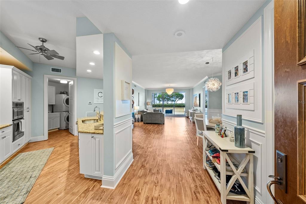 An entryway leads into an open-concept living area with light wood floors and white cabinetry — 470 MANDALAY AVENUE UNIT 303, CLEARWATER, FL