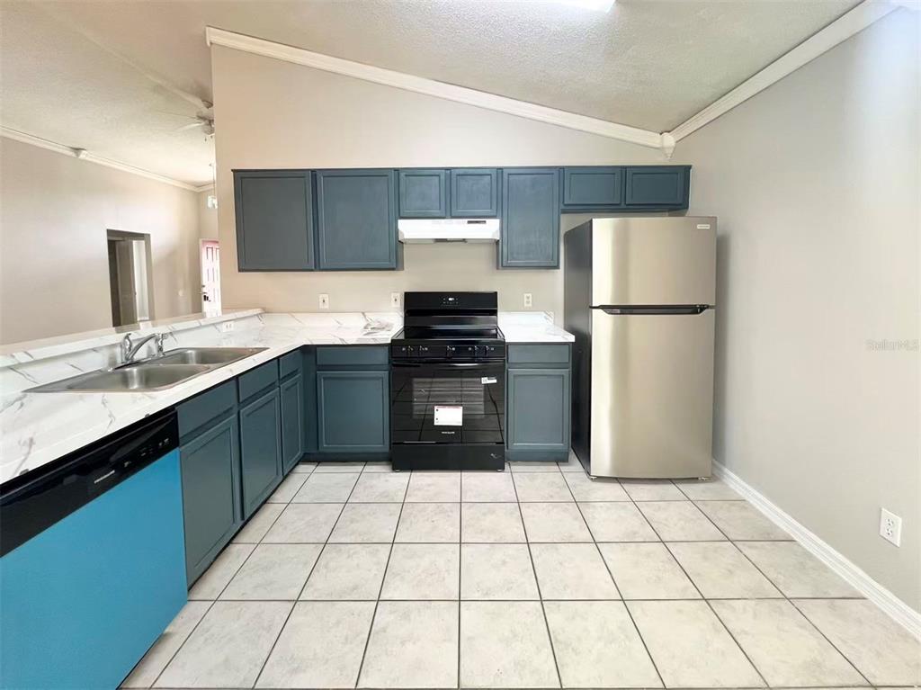 A kitchen features blue cabinets, stainless steel appliances, white countertops, and light-colored tiled flooring — 1275 ADIRONDACK COURT, APOPKA, FL