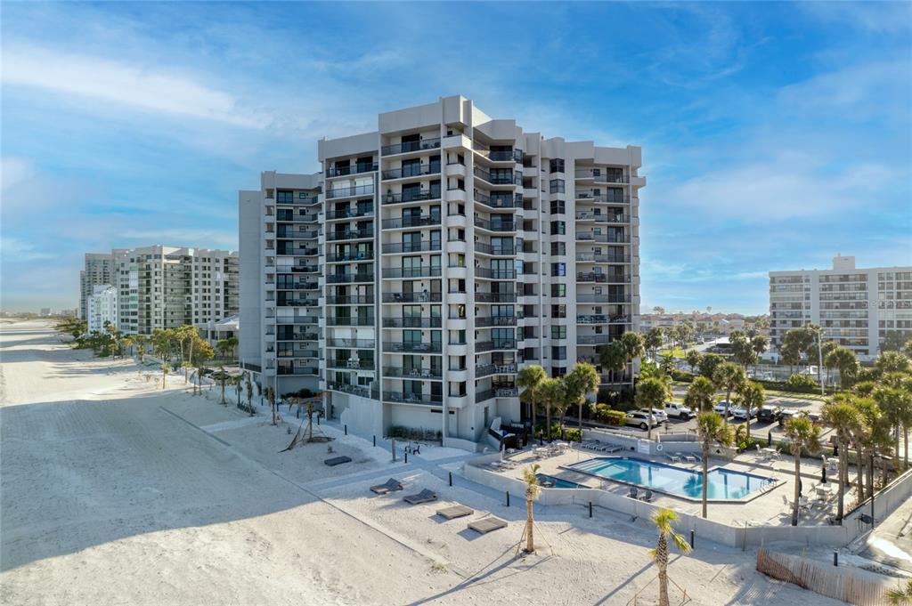 An aerial view of a multi-story beachfront condominium building with a pool and sandy beach — 1660 GULF BOULEVARD UNIT 807, CLEARWATER, FL