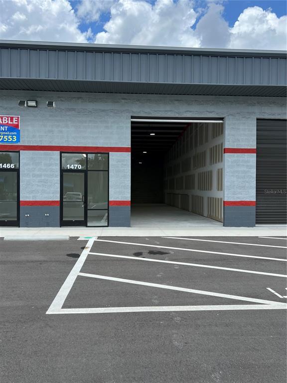 An exterior view of a commercial building with a glass door and an open bay — 1450 HAMLIN AVENUE, ST CLOUD, FL
