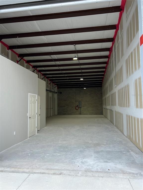 An empty industrial warehouse space features exposed steel beams, concrete floors, and unfinished drywall walls — 1450 HAMLIN AVENUE, ST CLOUD, FL