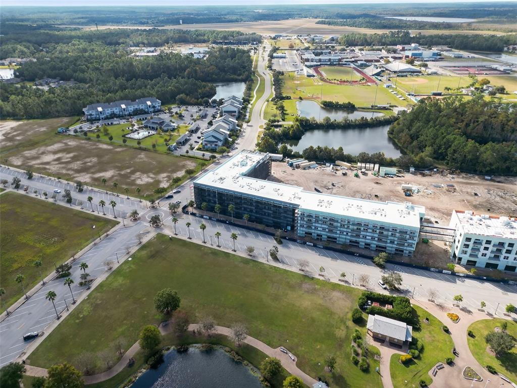 An aerial view shows a large multi-story apartment building under construction near a park — 890 CENTRAL AVENUE UNIT E101, PALM COAST, FL