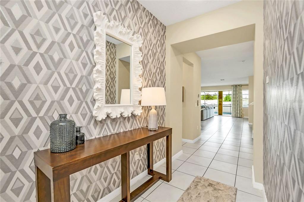 A hallway features geometric patterned wallpaper, a wooden console table, and a white framed mirror — 1576 NASSAU POINT TRAIL, KISSIMMEE, FL