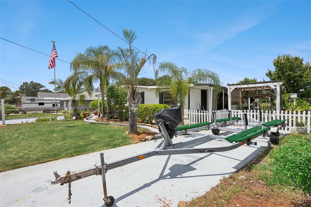 A single-story manufactured home with a concrete driveway, carport, and American flag in the yard — 109 DOUGLAS STREET, EDGEWATER, FL