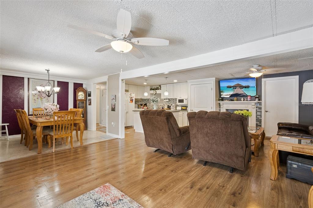 An open-concept living and dining area features wood-look flooring, a ceiling fan, and white cabinetry — 109 DOUGLAS STREET, EDGEWATER, FL