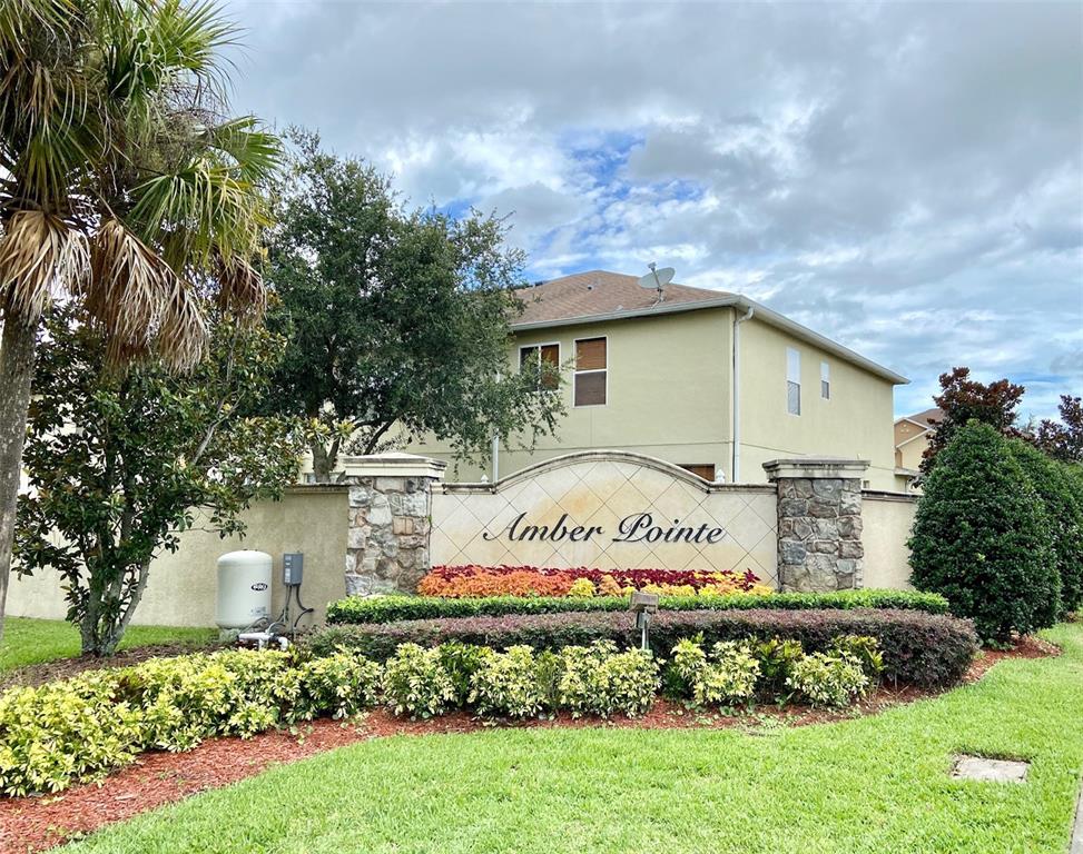 The exterior of the Amber Pointe community entrance features a stone-accented sign and landscaping — 2539 AVENTURINE STREET, KISSIMMEE, FL