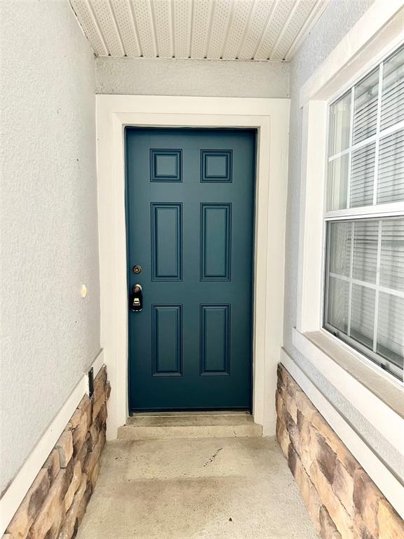 A teal six-panel front door is framed by stone veneer siding and a white window — 2539 AVENTURINE STREET, KISSIMMEE, FL