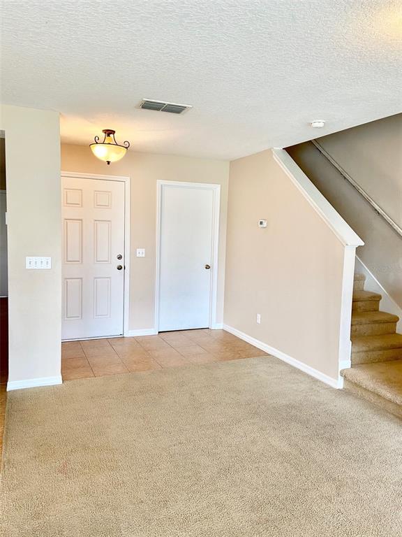 An entryway features tile flooring, a staircase, a front door, and a closet door — 2539 AVENTURINE STREET, KISSIMMEE, FL