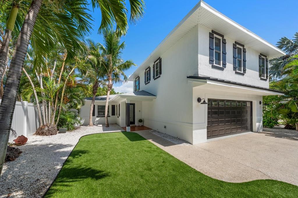 A two-story white house with a dark garage door, shutters, and a green lawn — 1907 BAY BOULEVARD, INDIAN ROCKS BEACH, FL