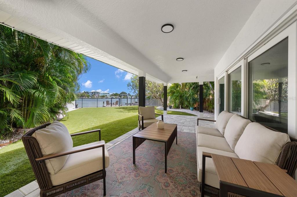 A covered outdoor patio features a seating area, a rug, and a view of water — 1907 BAY BOULEVARD, INDIAN ROCKS BEACH, FL