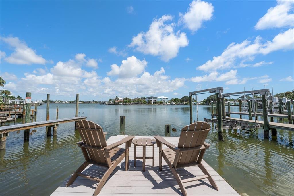 Two Adirondack chairs and a small table sit on a wooden dock overlooking the water — 1907 BAY BOULEVARD, INDIAN ROCKS BEACH, FL