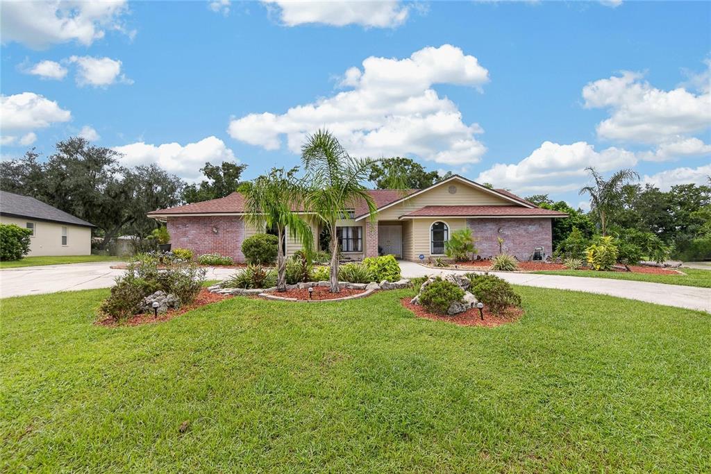 A single-story brick and siding house with a large lawn and palm trees — 2814 HAMMOCK DRIVE, PLANT CITY, FL