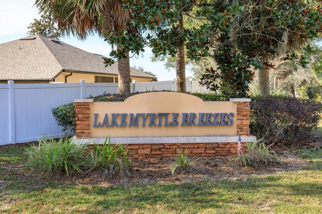 A stone and stucco monument sign for Lake Myrtle Breezes stands in a grassy yard — 1005 MYRTLE BREEZES COURT, FRUITLAND PARK, FL
