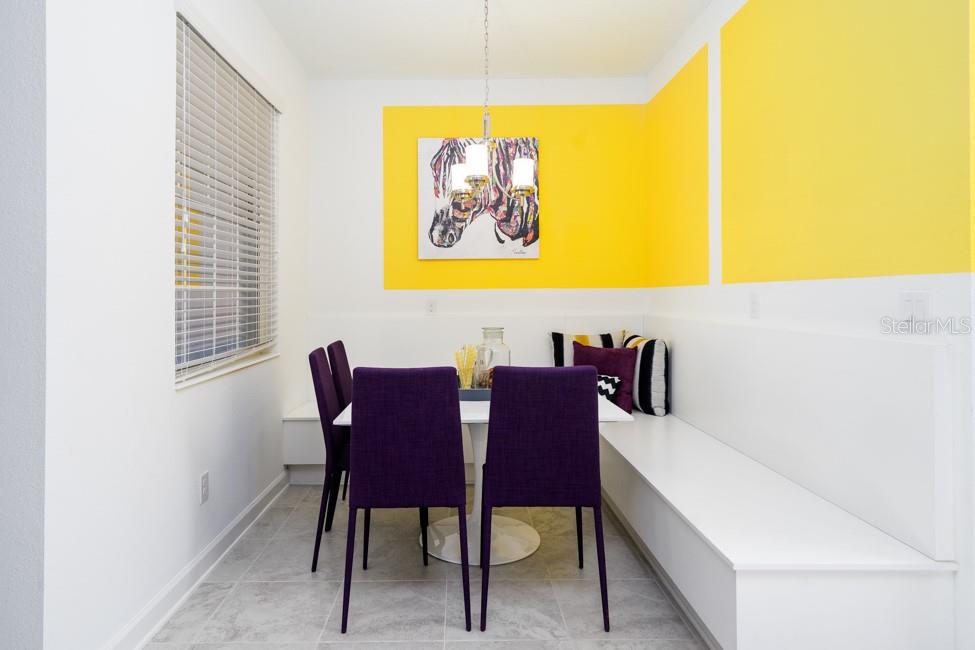 A dining nook features a white banquette, purple chairs, and yellow accent walls — 6028 MEDITATION DRIVE, CLERMONT, FL
