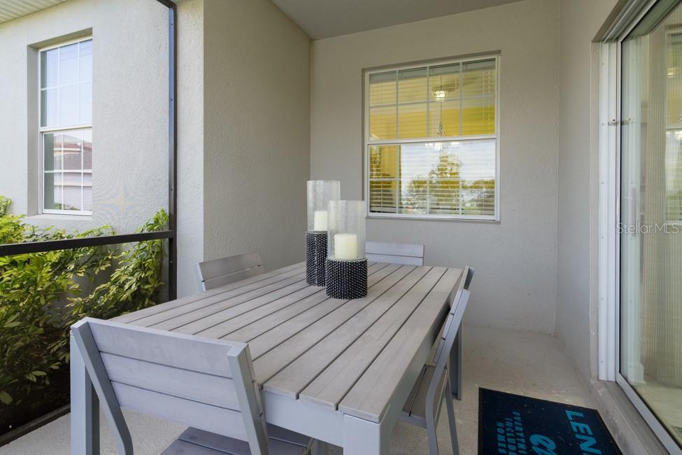 A covered patio features a gray wooden dining table with two candles and screen walls — 6028 MEDITATION DRIVE, CLERMONT, FL