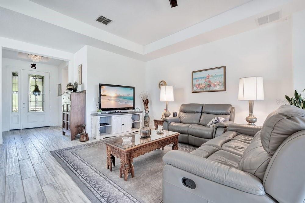 A living room features grey leather sofas, a wooden coffee table, and a white media console — 1314 EGGLESTON DRIVE, DELAND, FL