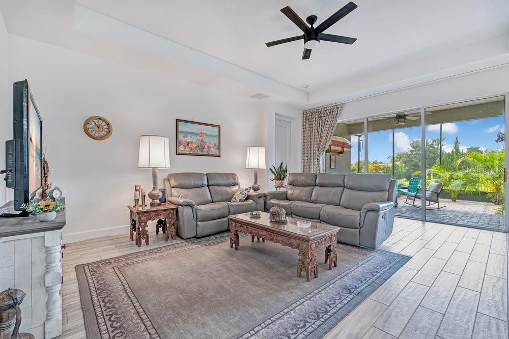 A living room features gray leather sofas, a wooden coffee table, and large sliding glass doors — 1314 EGGLESTON DRIVE, DELAND, FL