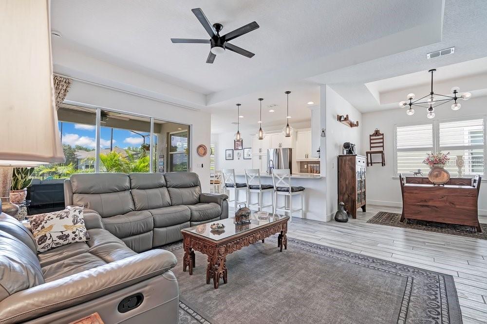 A living room with gray leather sofas, a carved wooden coffee table, and an open kitchen — 1314 EGGLESTON DRIVE, DELAND, FL