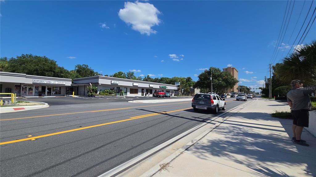 A view of a commercial strip mall building from a paved street with a sidewalk — 236 N AMELIA AVENUE, DELAND, FL