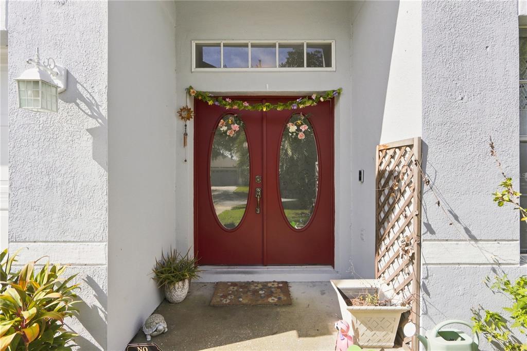 A red double front door with oval glass inserts sits under a rectangular transom window — 1732 NESTLEWOOD TRAIL, ORLANDO, FL