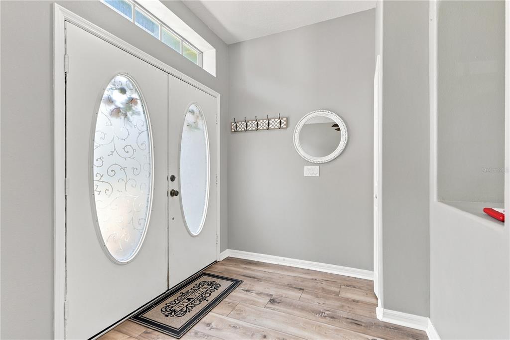 An entryway features a double front door, light gray walls, and wood-look flooring — 1732 NESTLEWOOD TRAIL, ORLANDO, FL