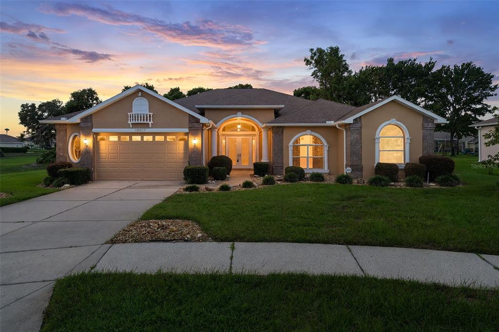 A single-story house with a tan stucco exterior, arched windows, and a two-car garage — 13417 WHITEHAVEN COURT, SPRING HILL, FL