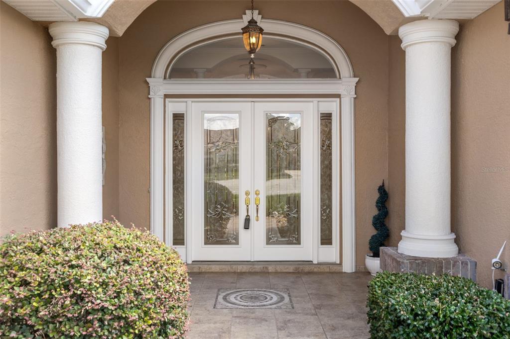 A front entryway features double glass-paneled doors flanked by columns and a decorative arched transom — 13417 WHITEHAVEN COURT, SPRING HILL, FL