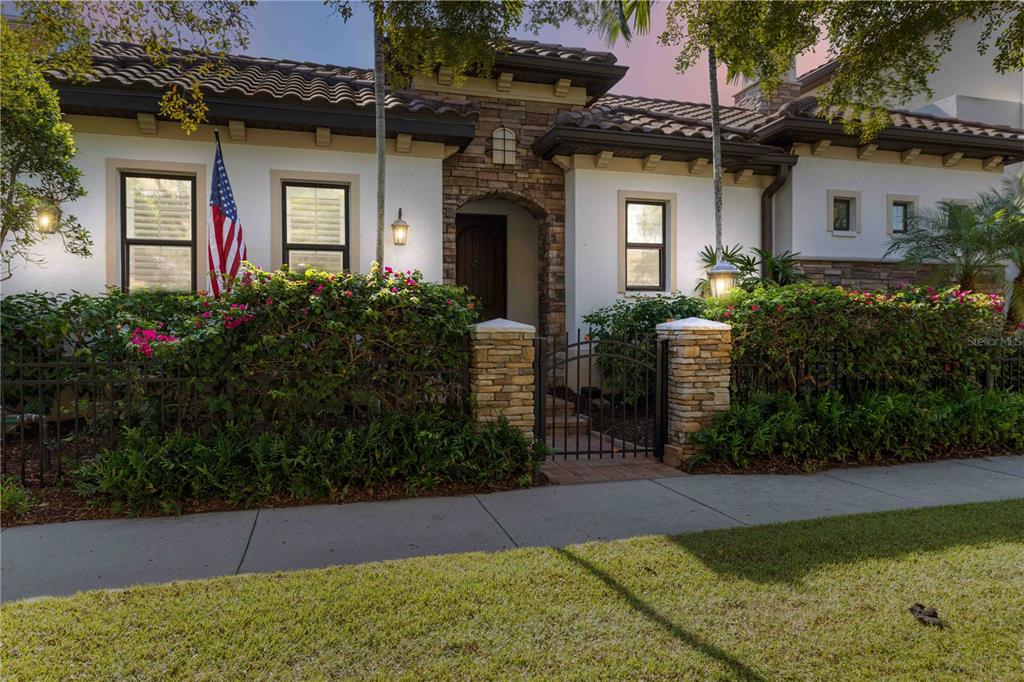 A single-story house with a stone entryway, tiled roof, and a gated front courtyard — 146 E TAMPA AVENUE, VENICE, FL
