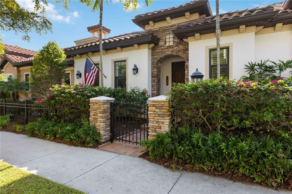 A Mediterranean-style house features a stone-accented entryway, a wrought-iron gate, and lush landscaping — 146 E TAMPA AVENUE, VENICE, FL