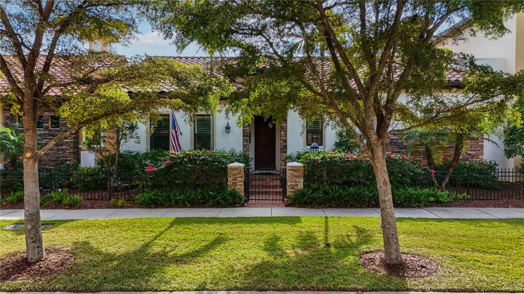 A single-story house with a tiled roof, stone accents, and a front courtyard with fencing — 146 E TAMPA AVENUE, VENICE, FL