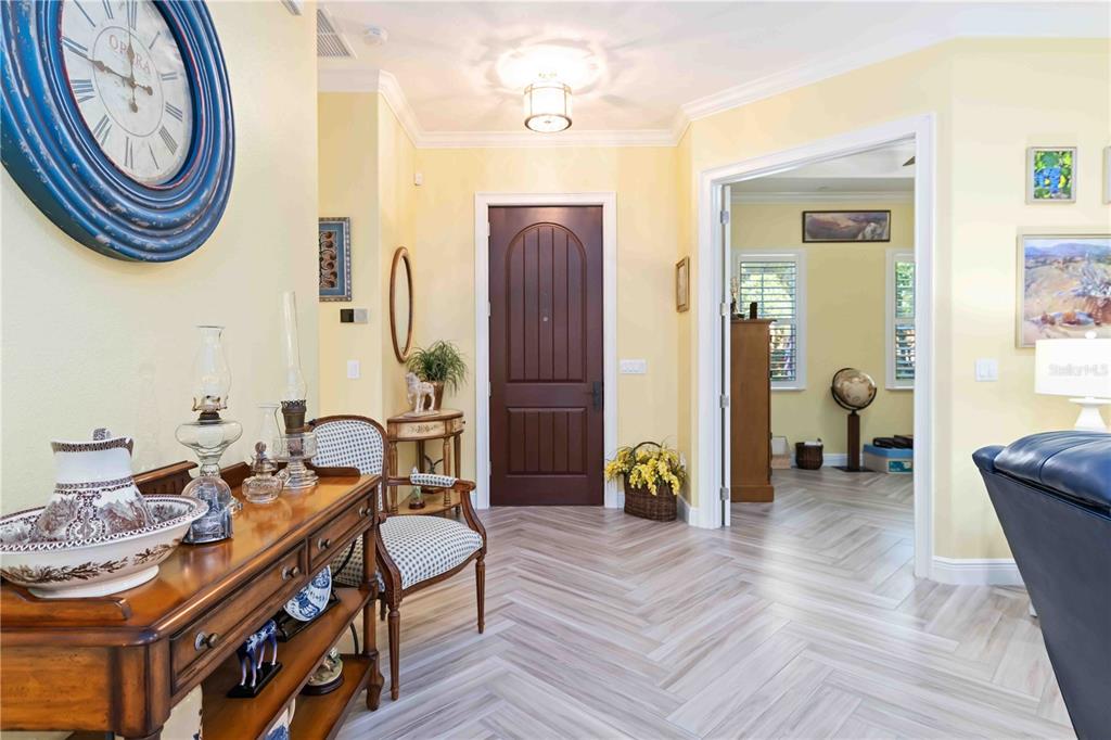 An entryway with light yellow walls, herringbone tile flooring, and a dark wood front door — 146 E TAMPA AVENUE, VENICE, FL