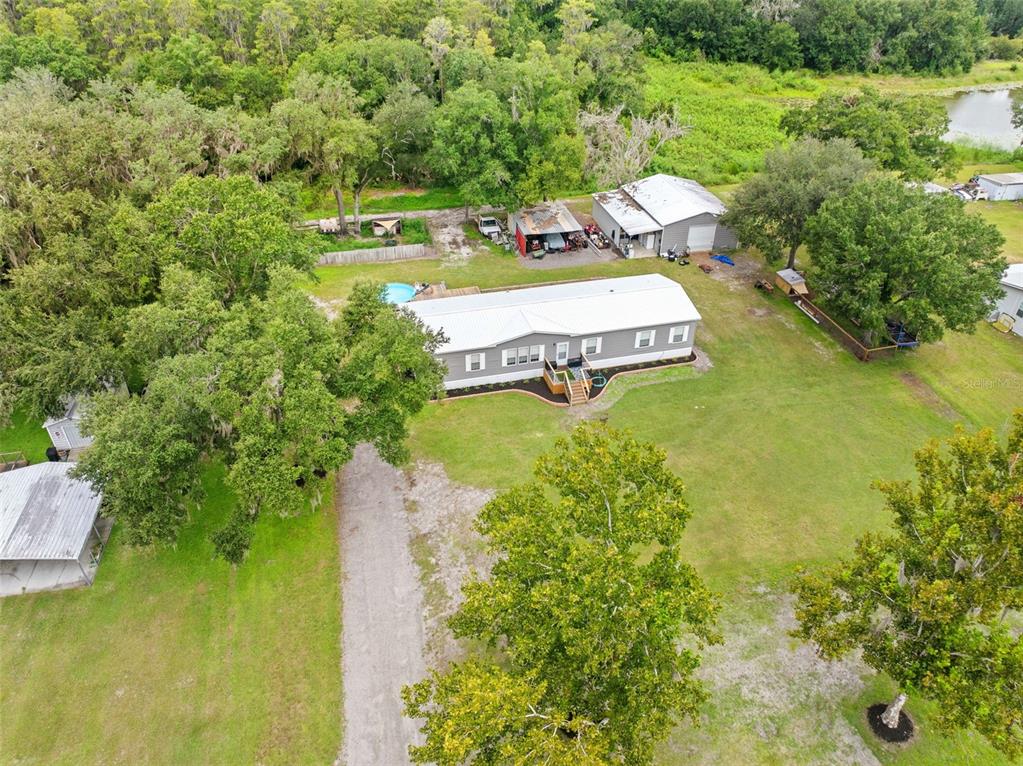 An aerial view shows a single-story house with a metal roof, pool, and detached garage — 4045 LOURY DRIVE, WESLEY CHAPEL, FL