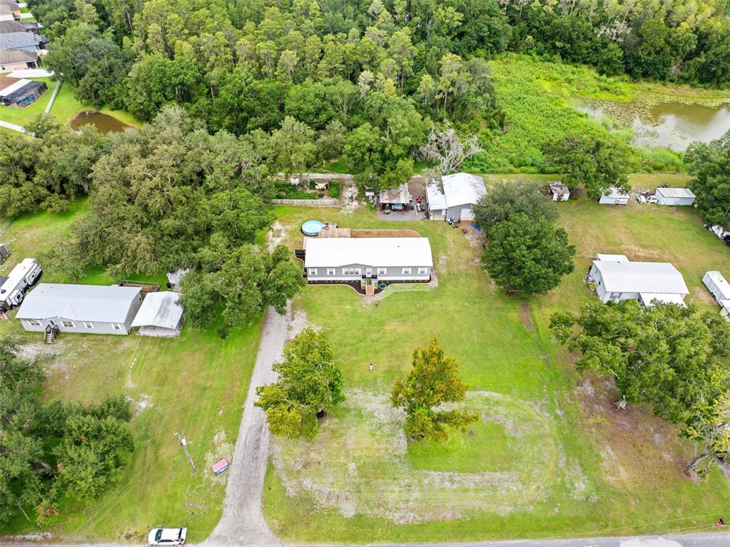 An aerial view shows a house with a pool, multiple outbuildings, and trees on a lot — 4045 LOURY DRIVE, WESLEY CHAPEL, FL
