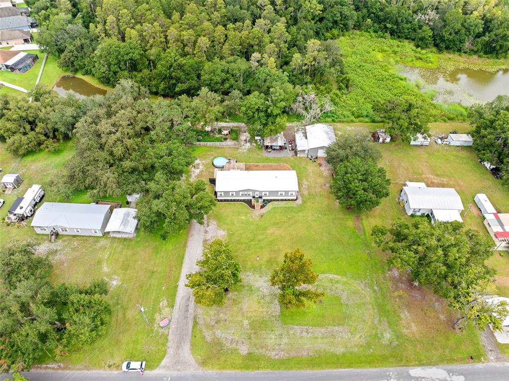 An aerial view shows a residential property with a main house, outbuildings, and a pool — 4045 LOURY DRIVE, WESLEY CHAPEL, FL