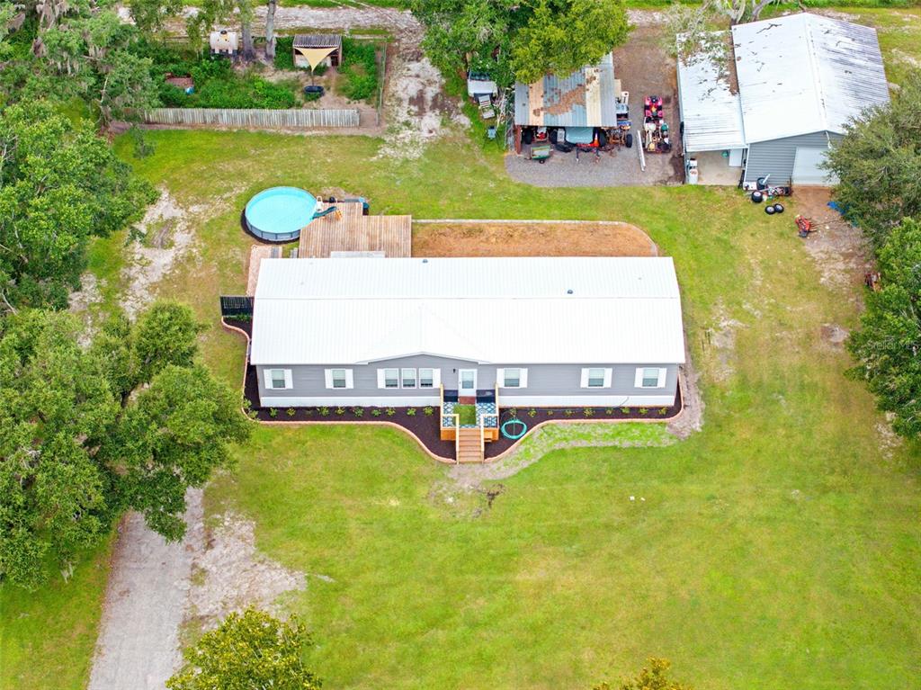 An aerial view shows a manufactured home with a metal roof, deck, and pool — 4045 LOURY DRIVE, WESLEY CHAPEL, FL