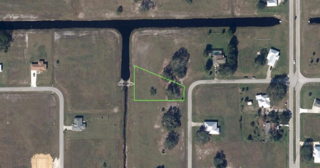 An aerial view shows a vacant, irregularly shaped lot outlined in green next to a canal — 432 MIRADOR DRIVE, SEBRING, FL