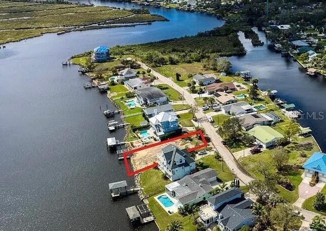 An aerial view shows a waterfront residential lot outlined in red along a canal — 989 SHOCKNEY DRIVE, ORMOND BEACH, FL