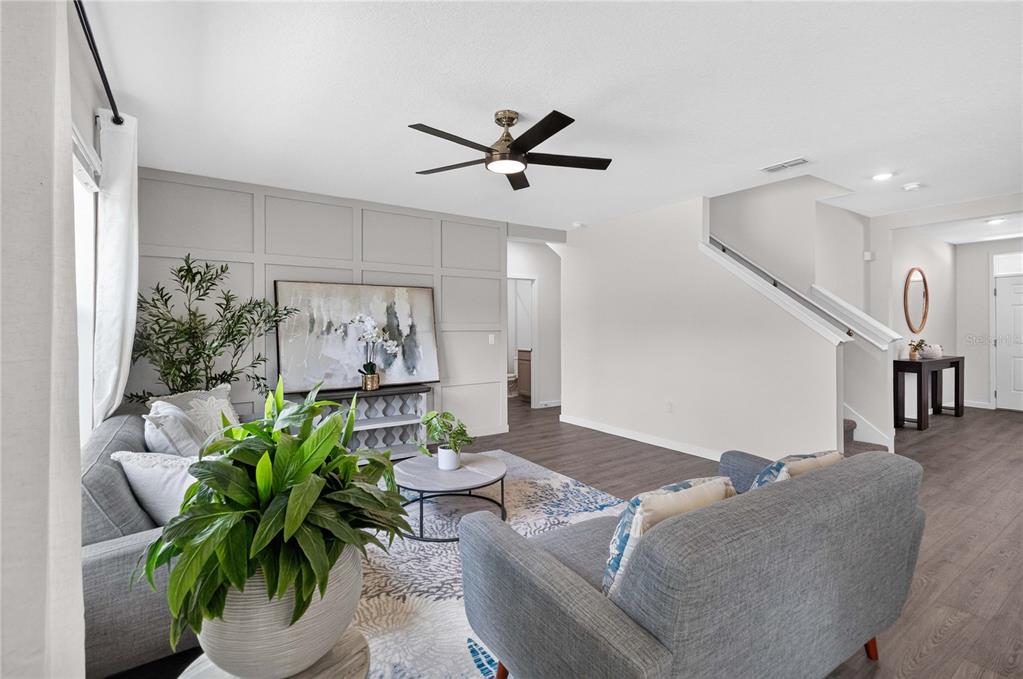 A living room features gray paneled walls, a ceiling fan, and two gray sofas — 1037 CHAMPION RIDGE DRIVE, DAYTONA BEACH, FL