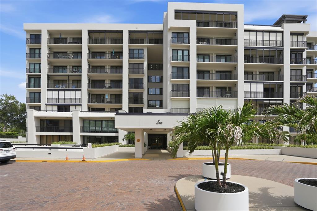 A multi-story apartment building with a paved driveway and palm trees in the foreground — 6 BELLEVIEW BOULEVARD UNIT 705, BELLEAIR, FL