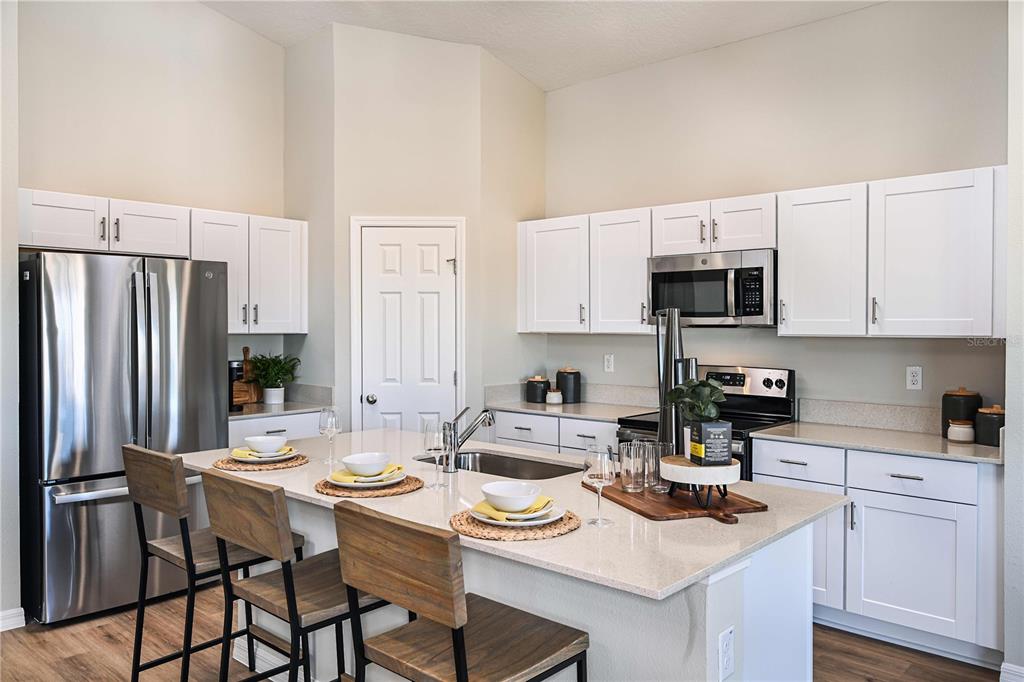 A modern kitchen features white cabinets, stainless steel appliances, and a large central island — 4156 RIVER BEACON BOULEVARD, DAVENPORT, FL
