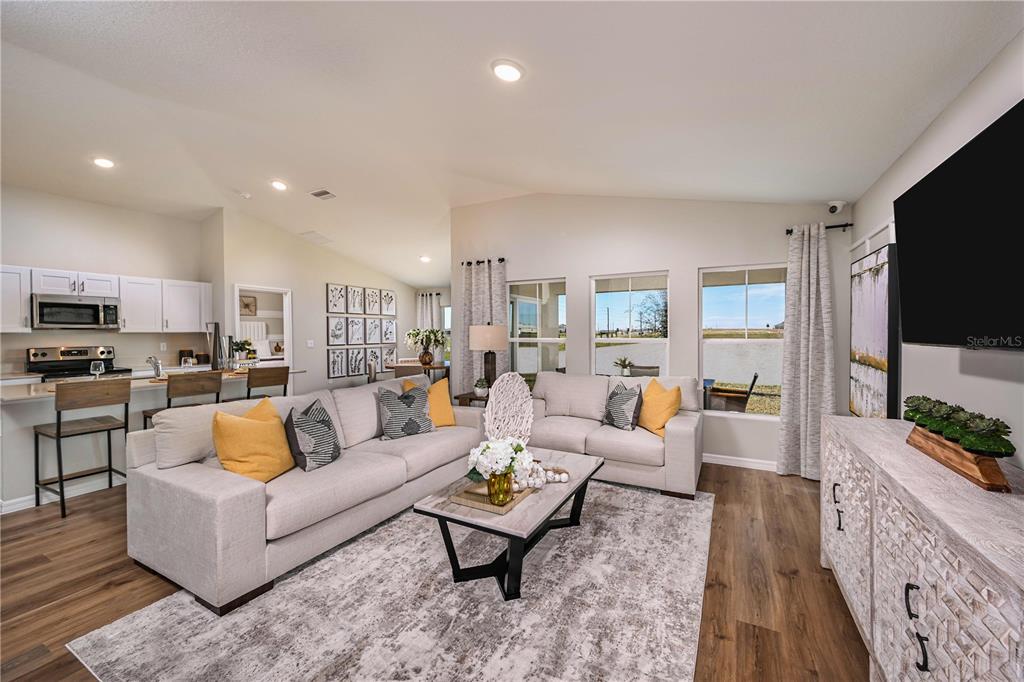 A living room with a beige sofa, coffee table, and open kitchen in the background — 4156 RIVER BEACON BOULEVARD, DAVENPORT, FL