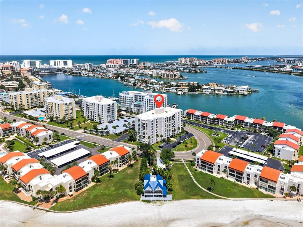 An aerial view shows a multi-story residential complex near a beach and a bay — 855 BAYWAY BOULEVARD UNIT 503, CLEARWATER, FL