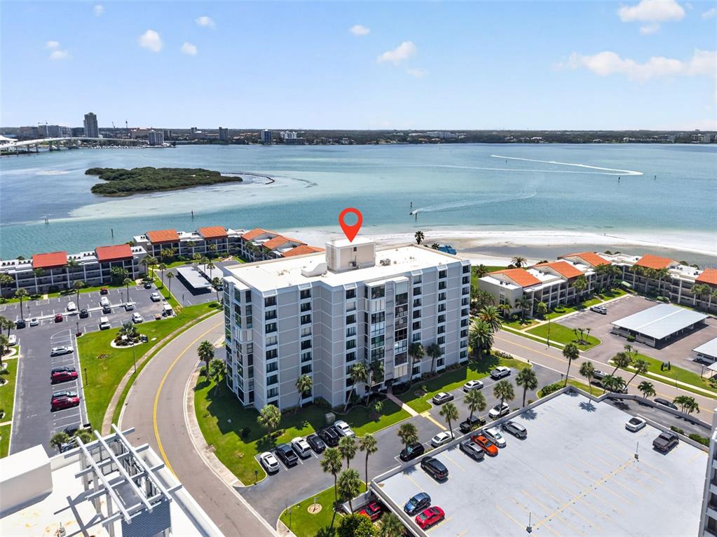An aerial view shows a multi-story apartment building near a beach and a parking lot — 855 BAYWAY BOULEVARD UNIT 503, CLEARWATER, FL