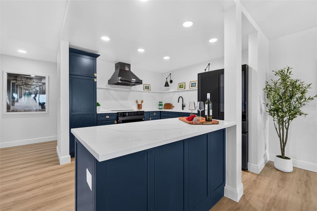 A kitchen features a blue island with a white countertop, dark cabinetry, and light flooring — 855 BAYWAY BOULEVARD UNIT 503, CLEARWATER, FL