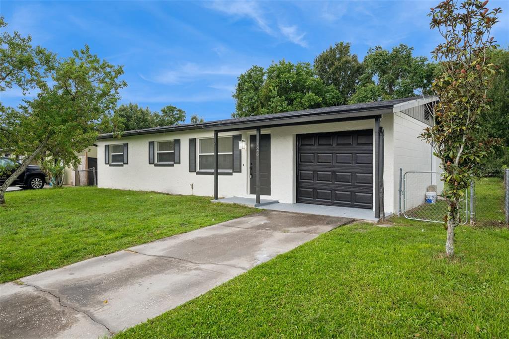 A single-story white house with a black garage door and a concrete driveway — 726 CORNELIA COURT, ORLANDO, FL